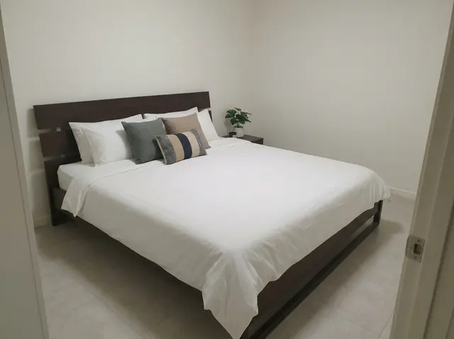 La même chambre après home staging virtuel : lit fait avec linge blanc, coussins, table de chevet et plante