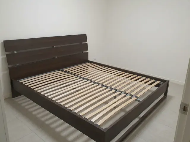 Chambre vide avec un simple sommier en bois, sans matelas ni décoration